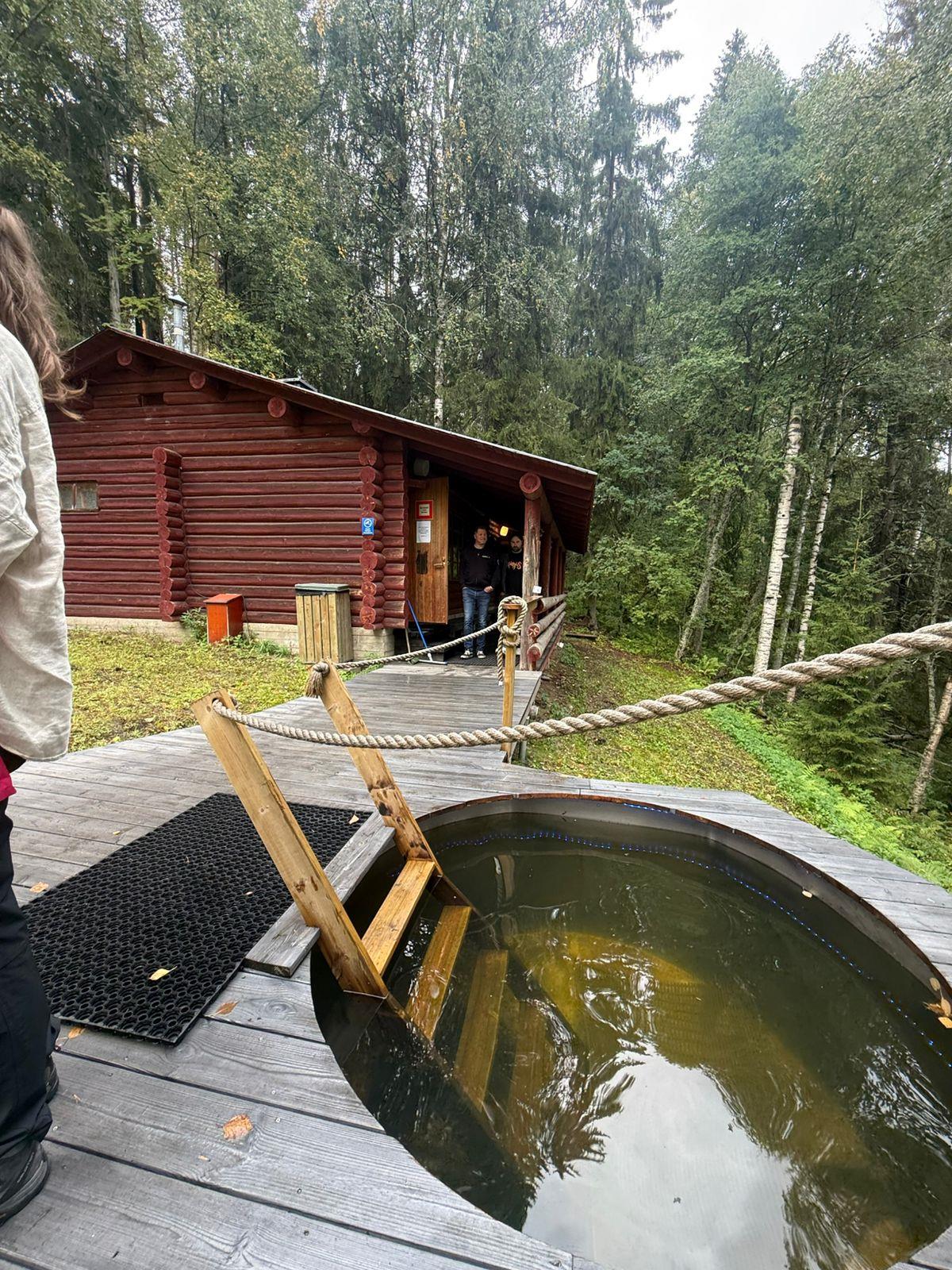 Outdoor hot tub next to a log sauna at Lykynlampi