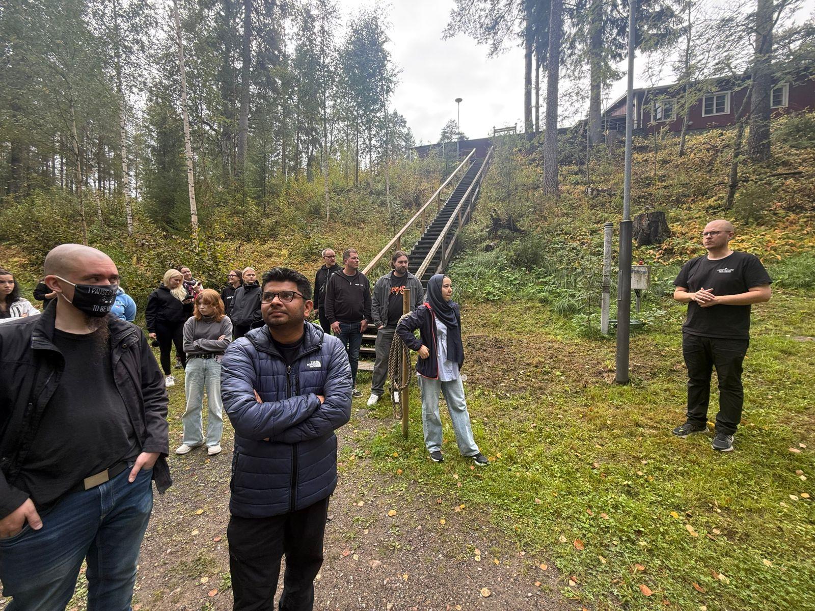 Group standing outdoors beside long wooden stairs at Lykynlampi