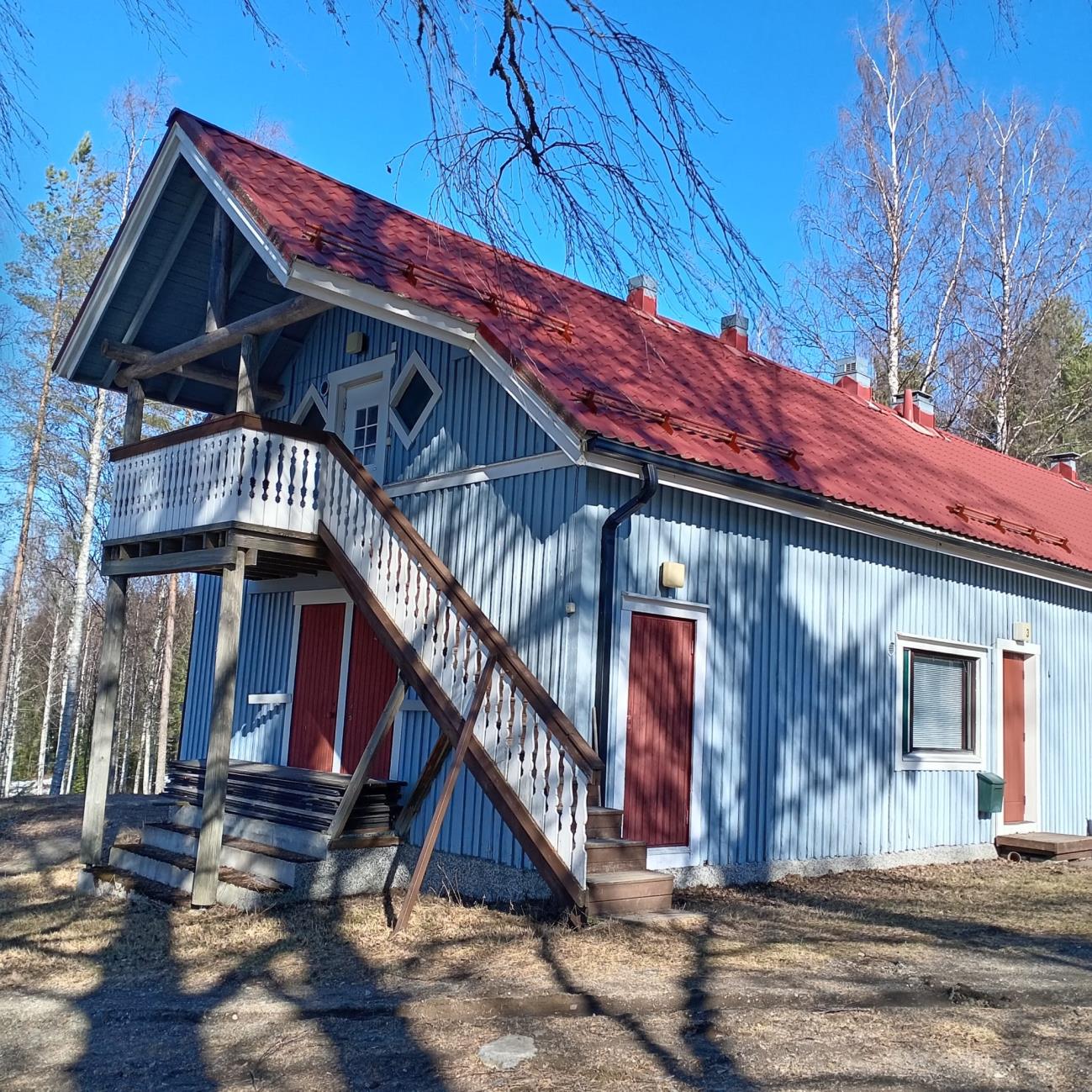 Blue wooden building with a red roof at Koli Freetime
