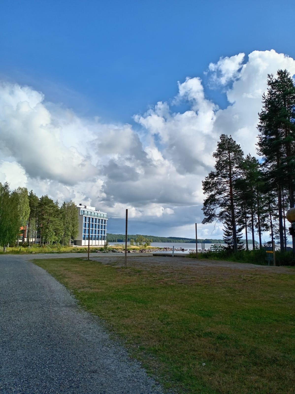 Path toward a lakeside hotel under a cloudy sky at Bomba